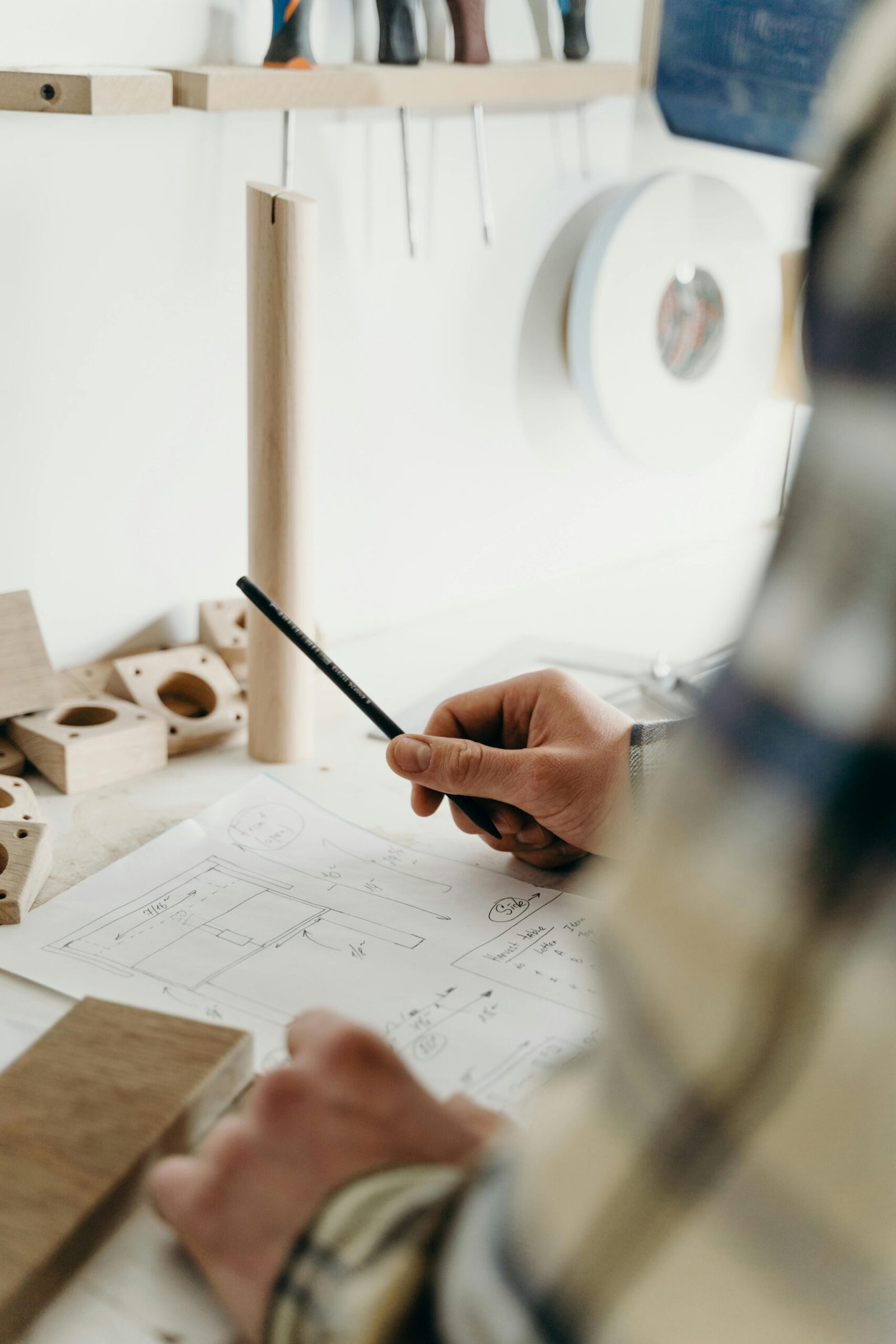 Focused hands of a carpenter sketching a design in a woodworking studio.